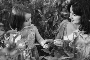 A vintage black and white photo series showing someone smelling flowers in a garden setting.
