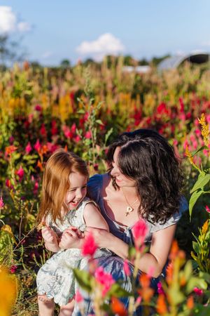 A couple embraces in a vibrant field of colorful flowers on a sunny day.