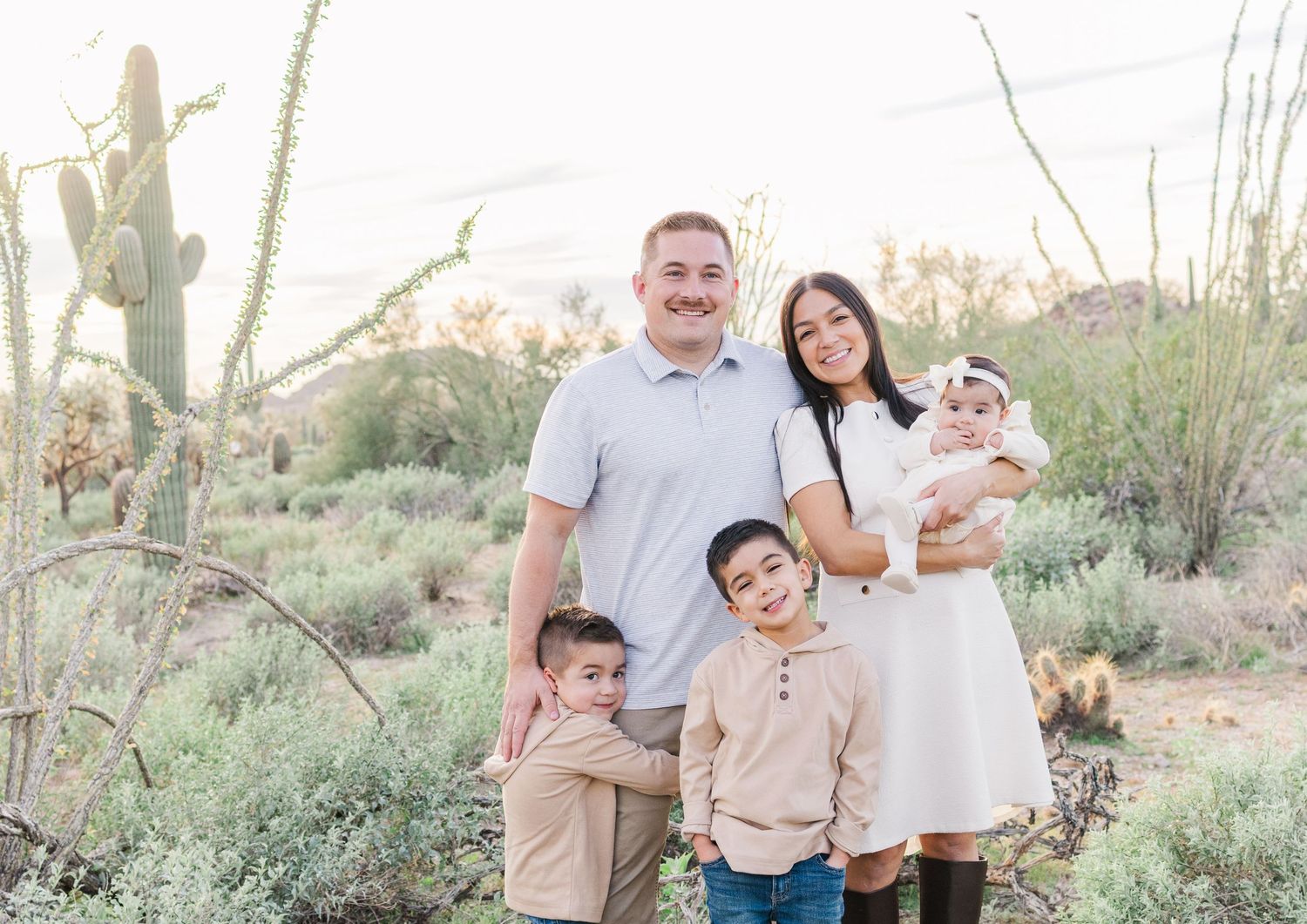 Family of 5 with young children smiling in the middle of the Arizona desert in a light and airy portrait.