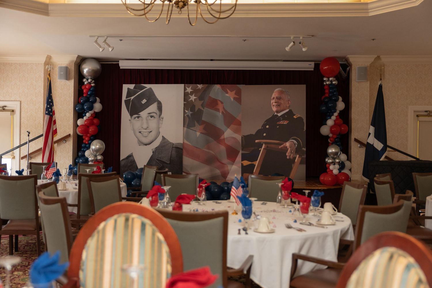 Decorated banquet room with red and black balloon arrangements and large photographs displayed on the wall.