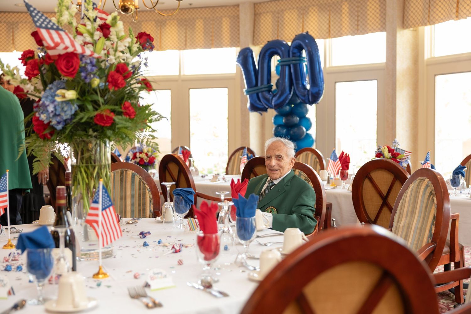 Patriotic table settings with American flags and red, white, and blue decorations at an elegant indoor event.