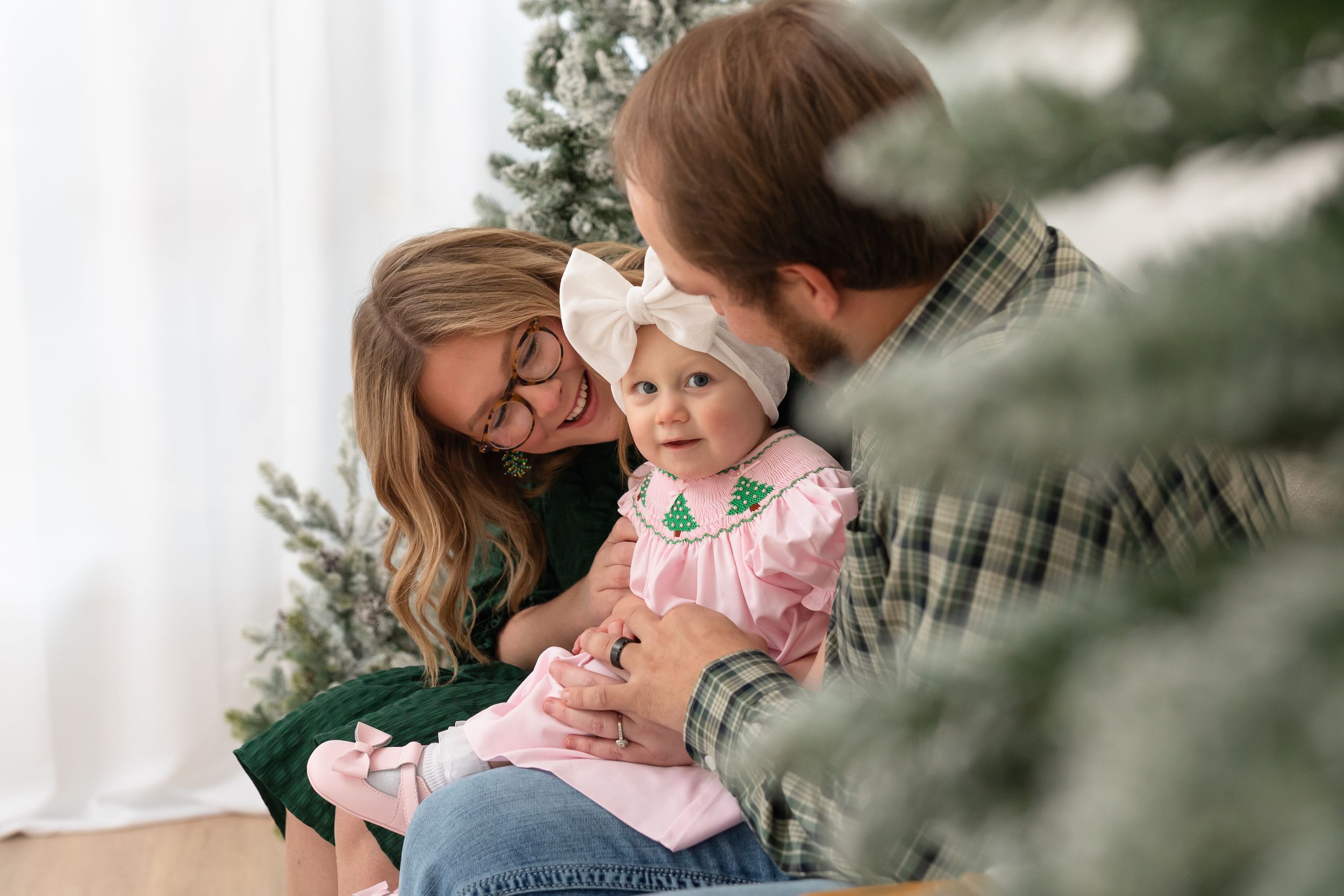 A family shares tender moments together during an outdoor photo session in soft natural lighting.