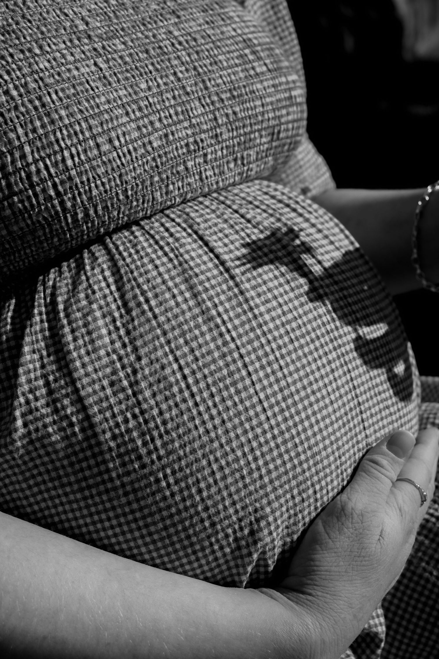 Close-up black and white detail shots of pregnant belly in textured fabric at a central coast maternity photoshoot.