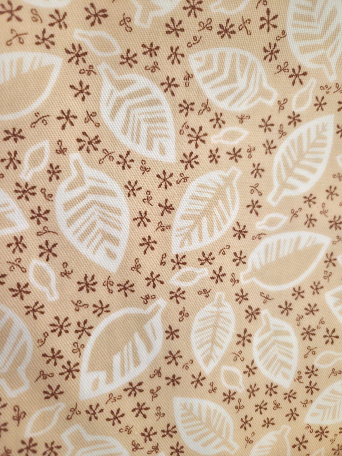 Delicate floral pattern with white palm leaves and small brown flowers on a beige background creates an elegant textile design.
