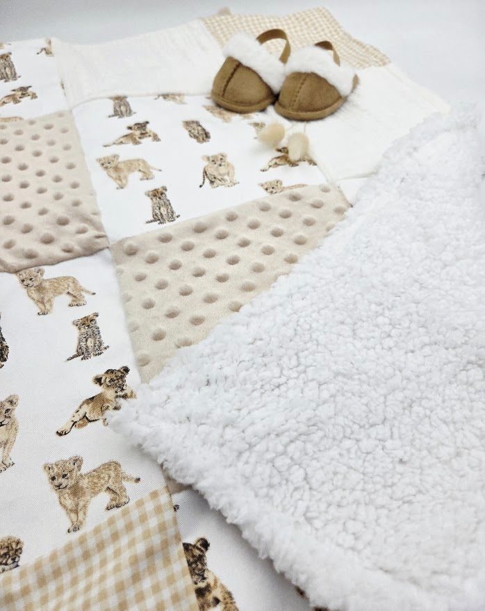 Baby blanket with gingham pattern and puppy print design next to white plush fabric.
