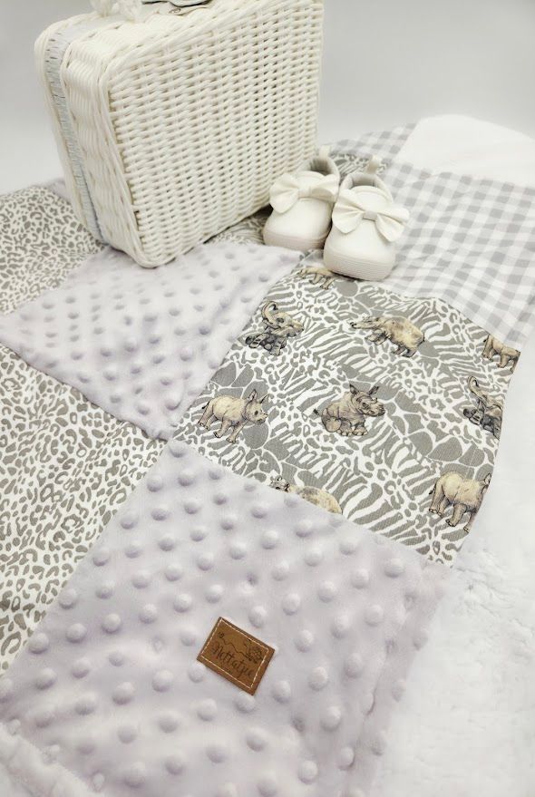 White and gray patchwork baby blanket with minky fabric, displayed with white wicker basket and tiny baby shoes.