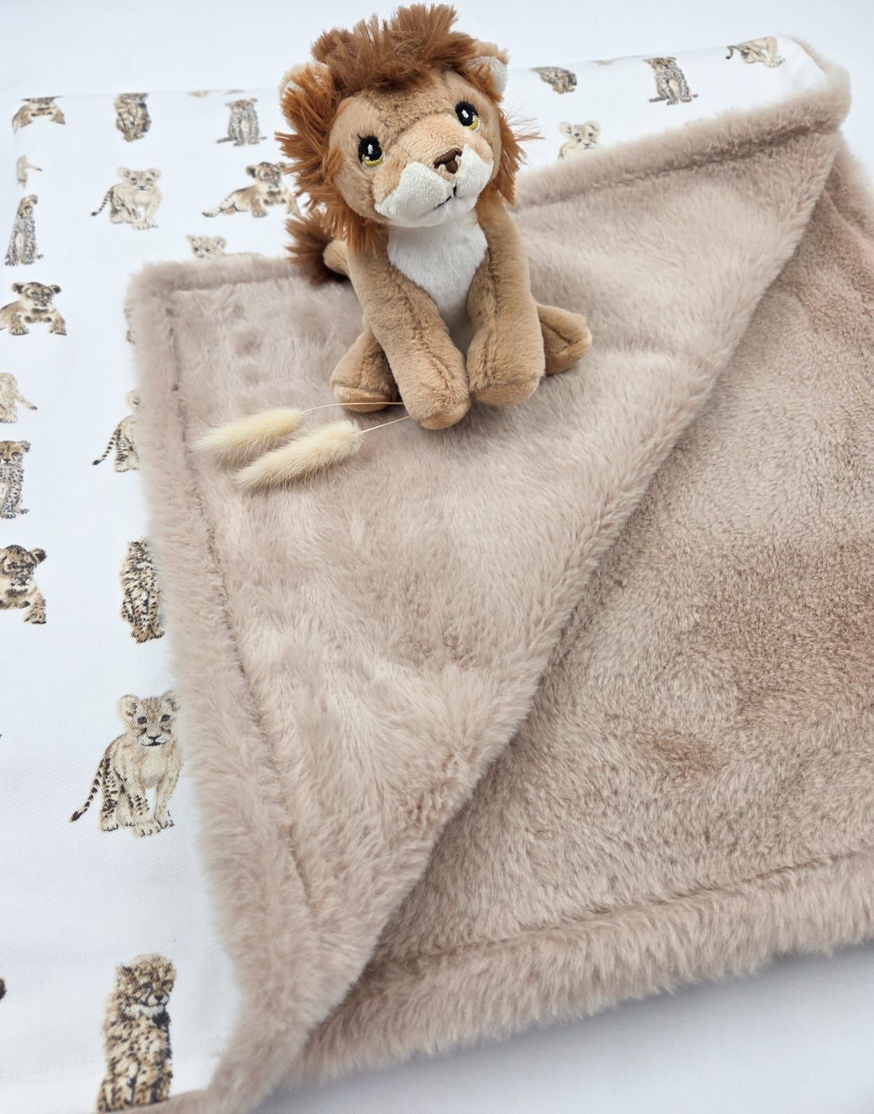 A soft beige plush baby security blanket with an attached lion stuffed animal head in the corner.