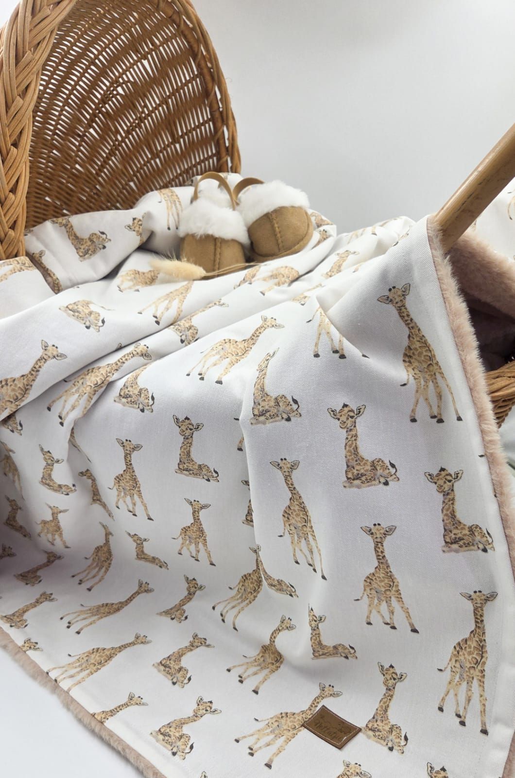 White fabric with repeating gold giraffe pattern displayed against woven basket background.