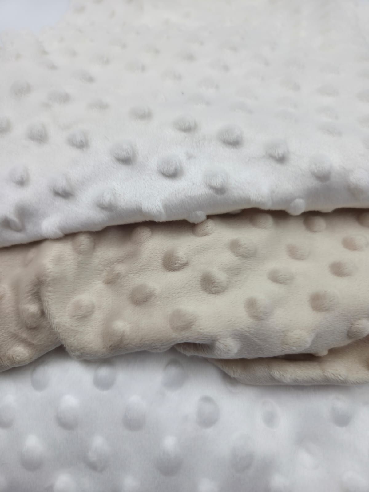 Close-up view of white minky dot fabric texture showing raised circular bumps in a repeating pattern.