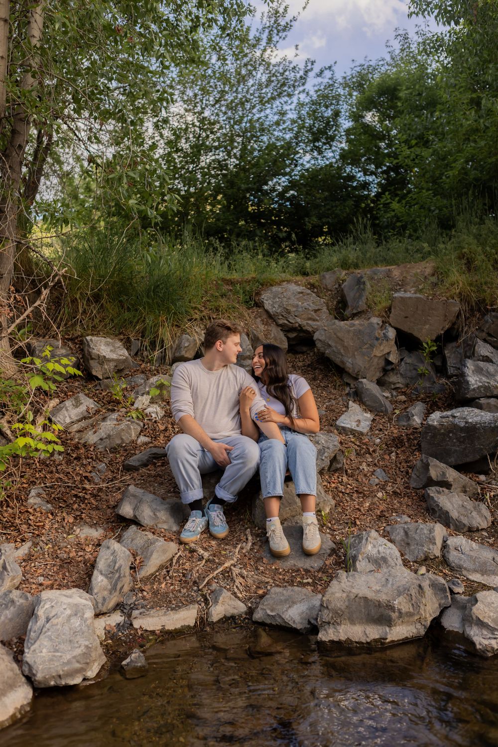 couple sitting together by a creek during a relaxed couples photo session in Utah