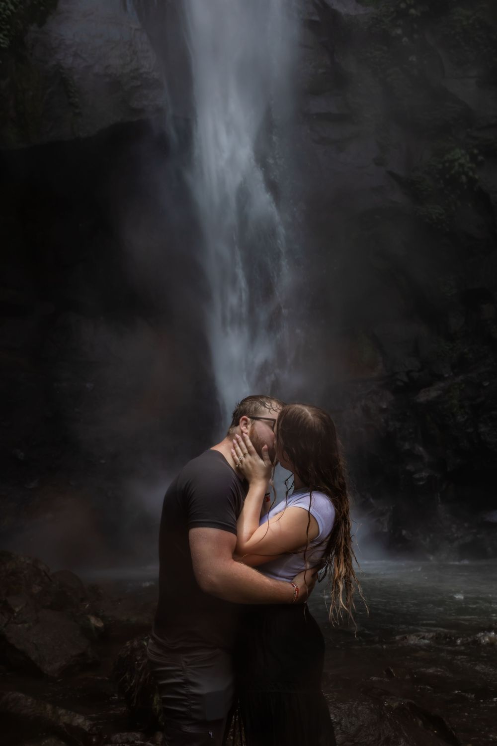 couple embracing in front of a waterfall during a destination couples photo session