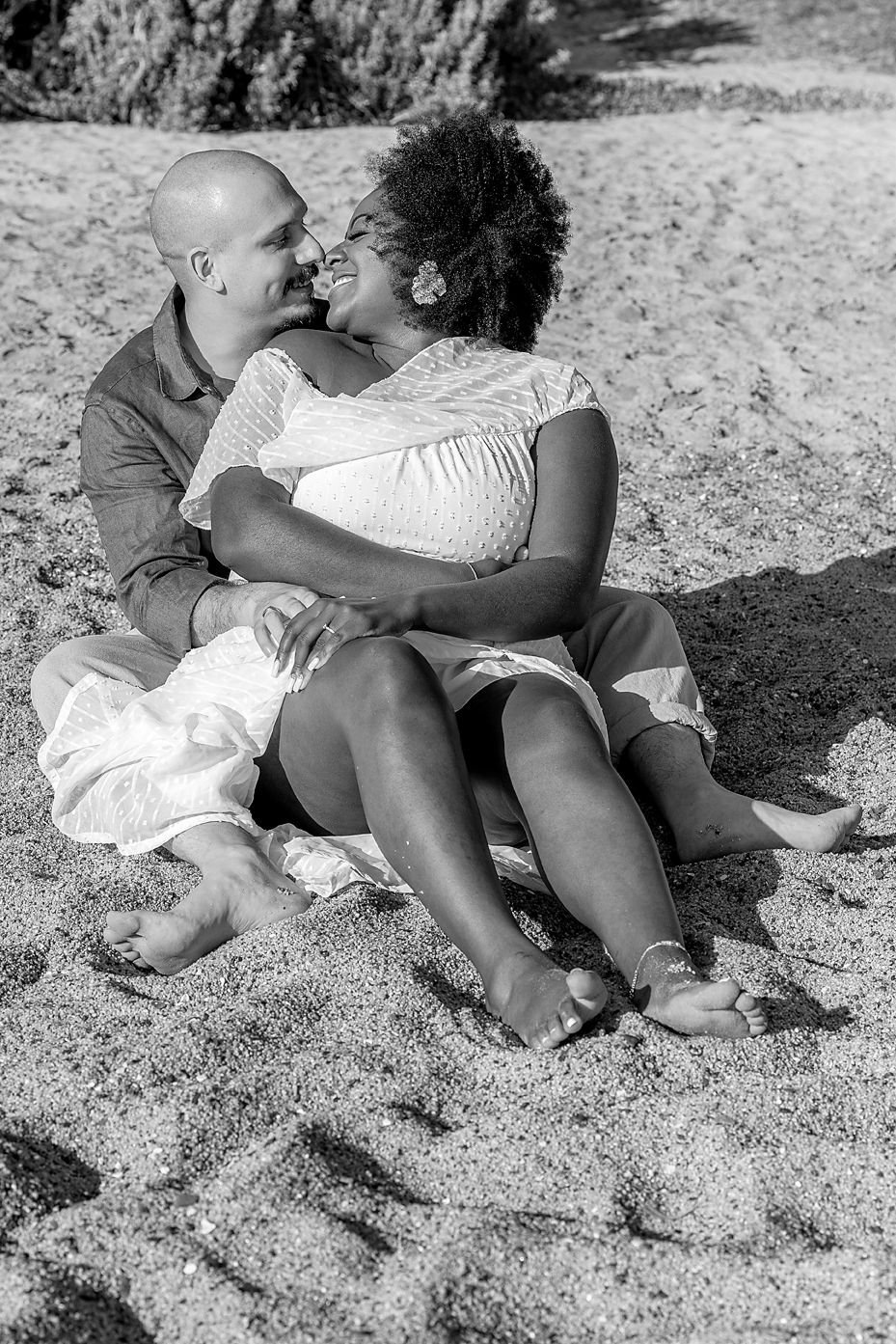 A sequence of black and white photos showing two people sitting together on a sandy beach.