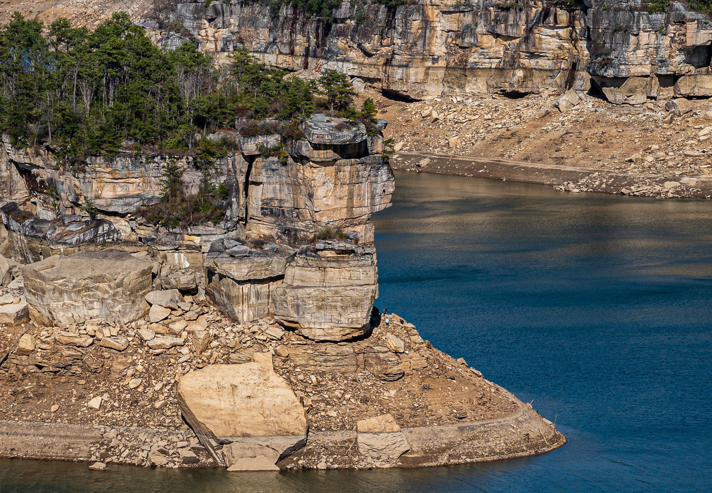 Limestone cliffs and rocky outcrops line the shoreline of a deep blue Summersville Lake located in West Virginia.