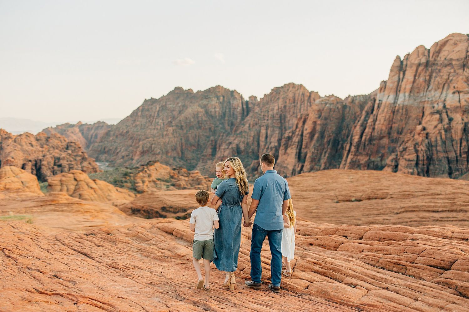 Hikers explore the vibrant red rock formations and rugged terrain of Snow Canyon State Park in Utah during sunset.