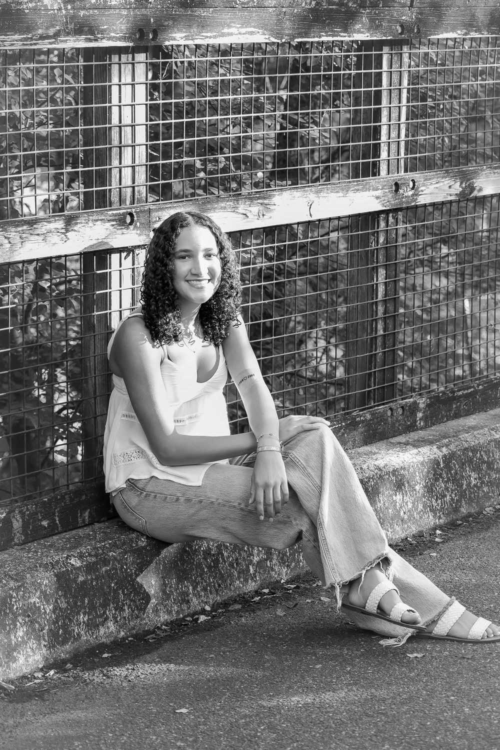 Black and white photo series showing a person sitting casually against a brick wall wearing a white top and sandals.