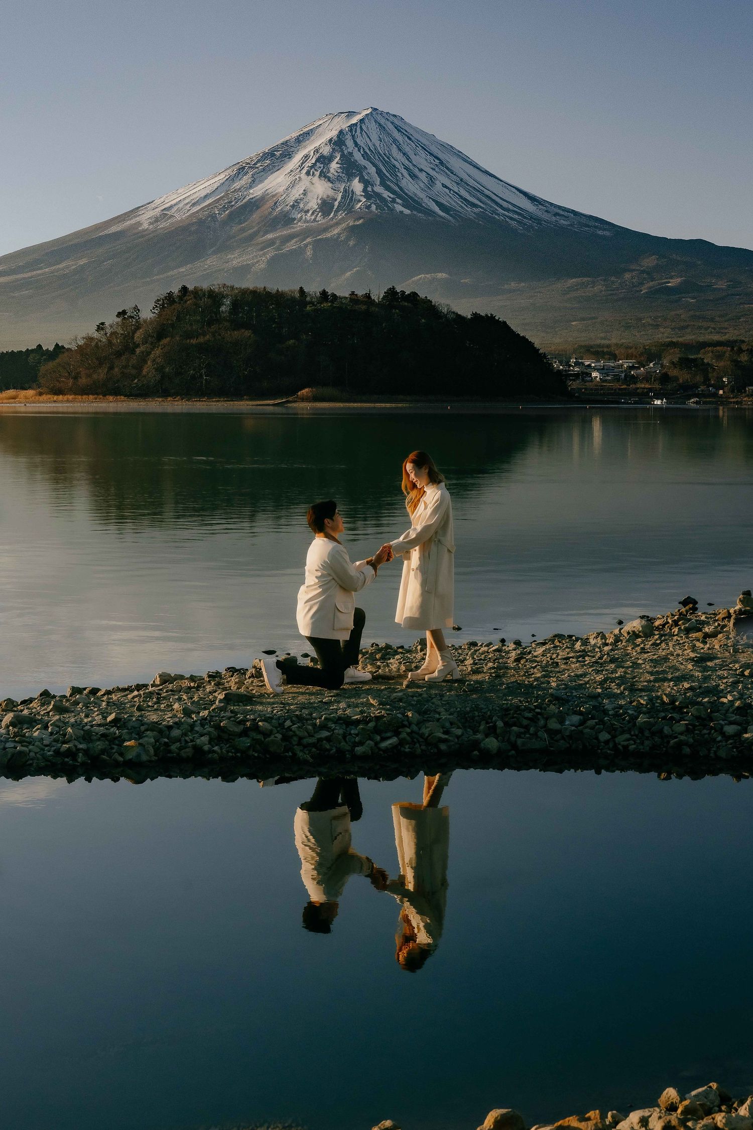 A romantic proposal scene unfolds by Lake Kawaguchiko with Mount Fuji creating a stunning backdrop in Japan.