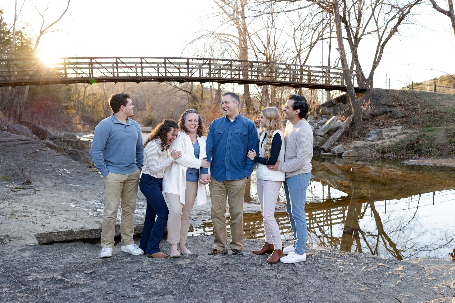 A group gathers on a rustic wooden bridge during golden hour for outdoor photos in a natural setting.