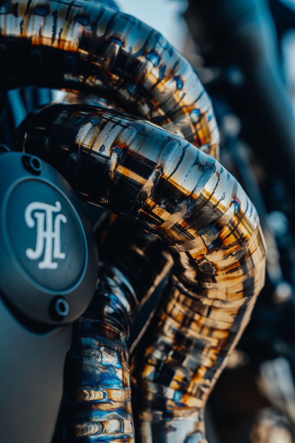 Artistic macro shot of multiple motorcycle fork tubes with JF logo emblems in moody blue lighting.