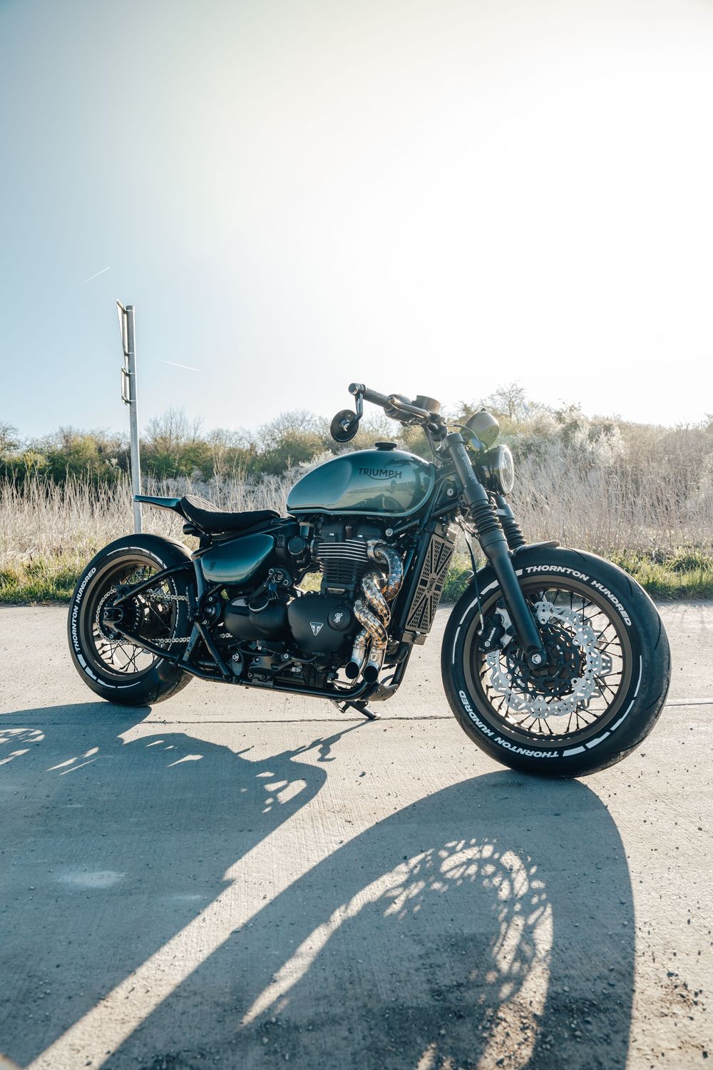 Custom black cafe racer motorcycle photographed from multiple angles on asphalt with dramatic shadows.