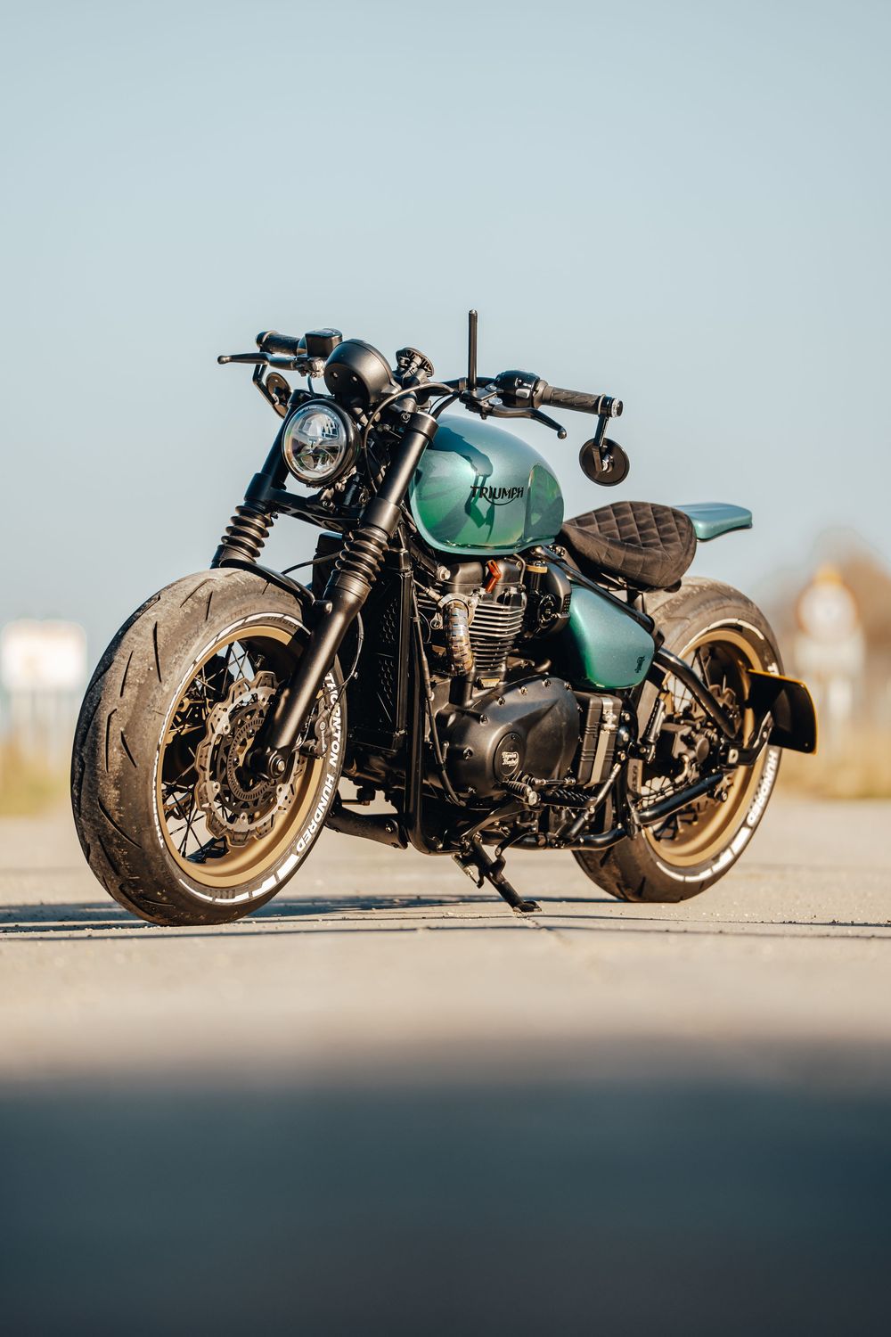 Custom turquoise cafe racer motorcycle with low profile design photographed from multiple angles on concrete.