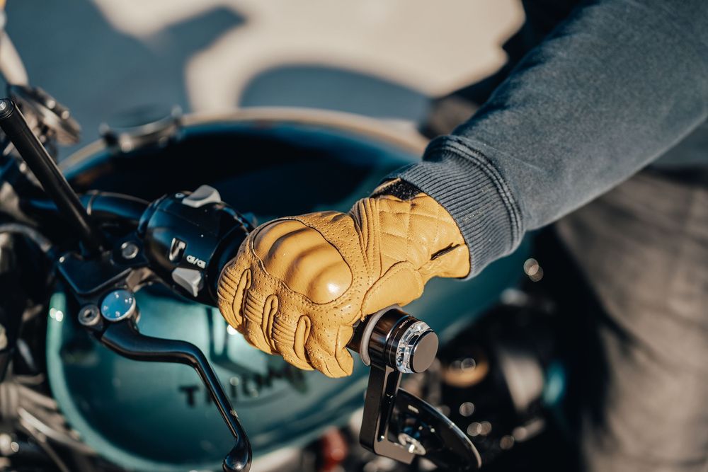 Close-up detail of a motorcycle rider's gloved hand gripping the handlebar controls.