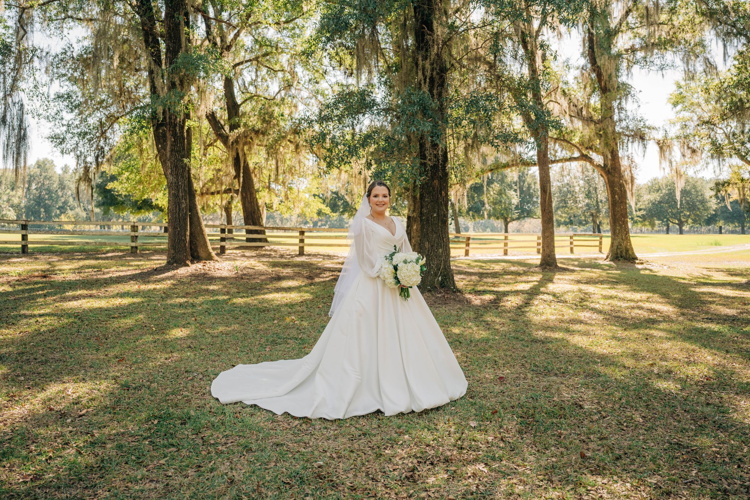 A couple shares a romantic moment in a sun-dappled forest setting during their outdoor wedding photoshoot.