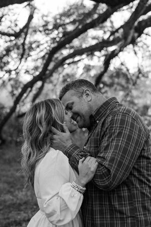A romantic couple shares tender moments in a series of black and white photos under tree branches.