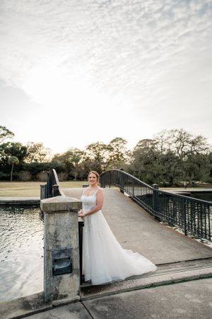 Bridal portraits on a stone bridge overlooking water during golden hour.