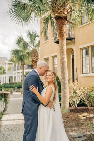 A couple shares romantic moments under palm trees outside a Mediterranean-style building in Florida.