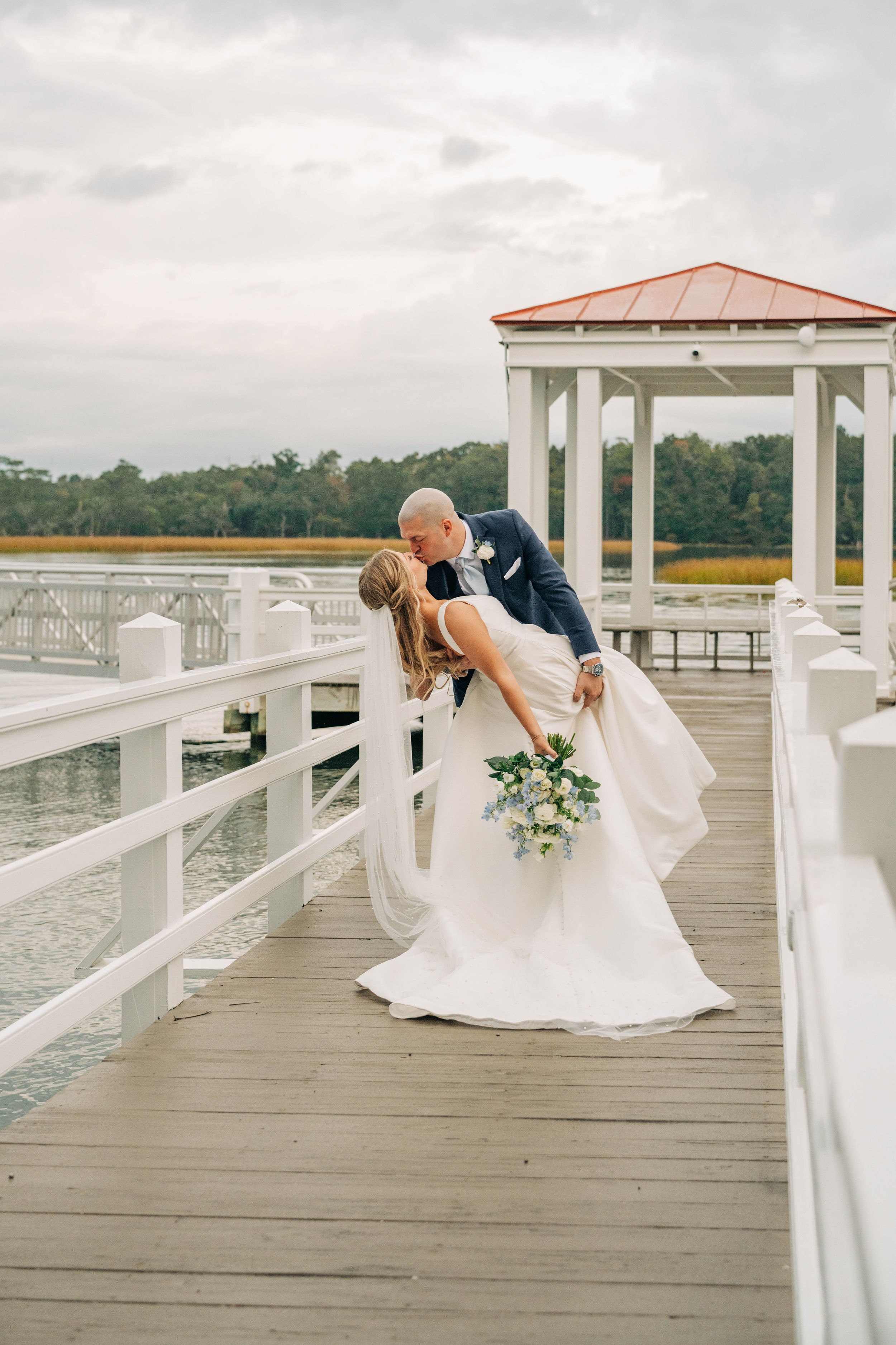 A romantic wedding photoshoot sequence on a white waterfront dock with a gazebo and water views in the background.