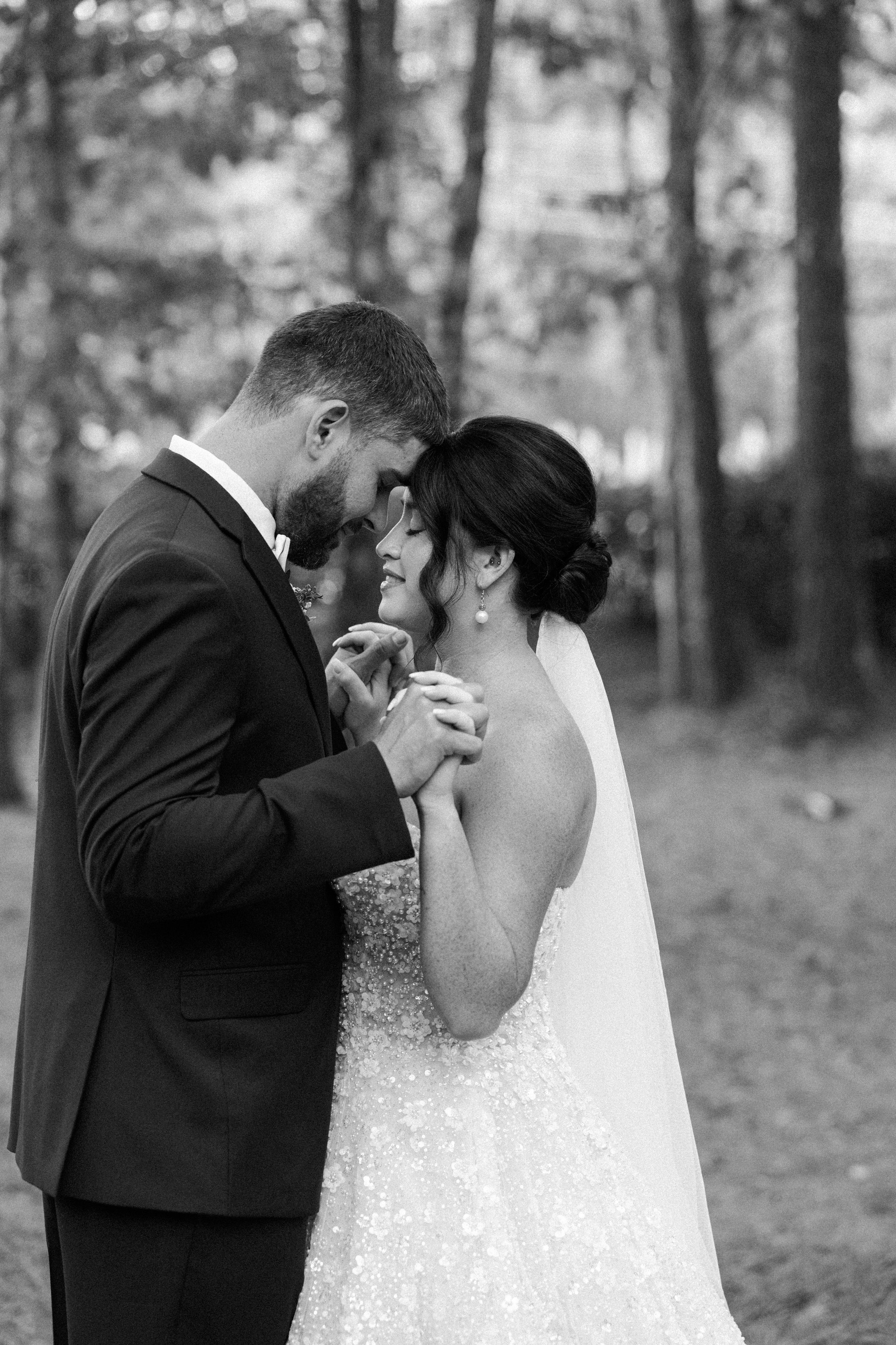 Black and white wedding photos show intimate moments between newlyweds sharing romantic kisses in a forest setting.
