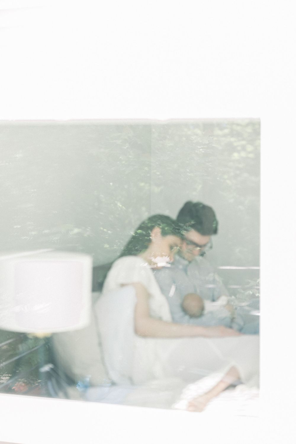 image of a mom and dad holding their baby through glass photographed by a Northern Virginia Newborn Photographer