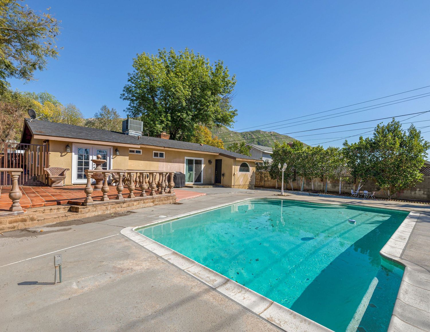 Long rectangular swimming pool at residential complex surrounded by trees and buildings.