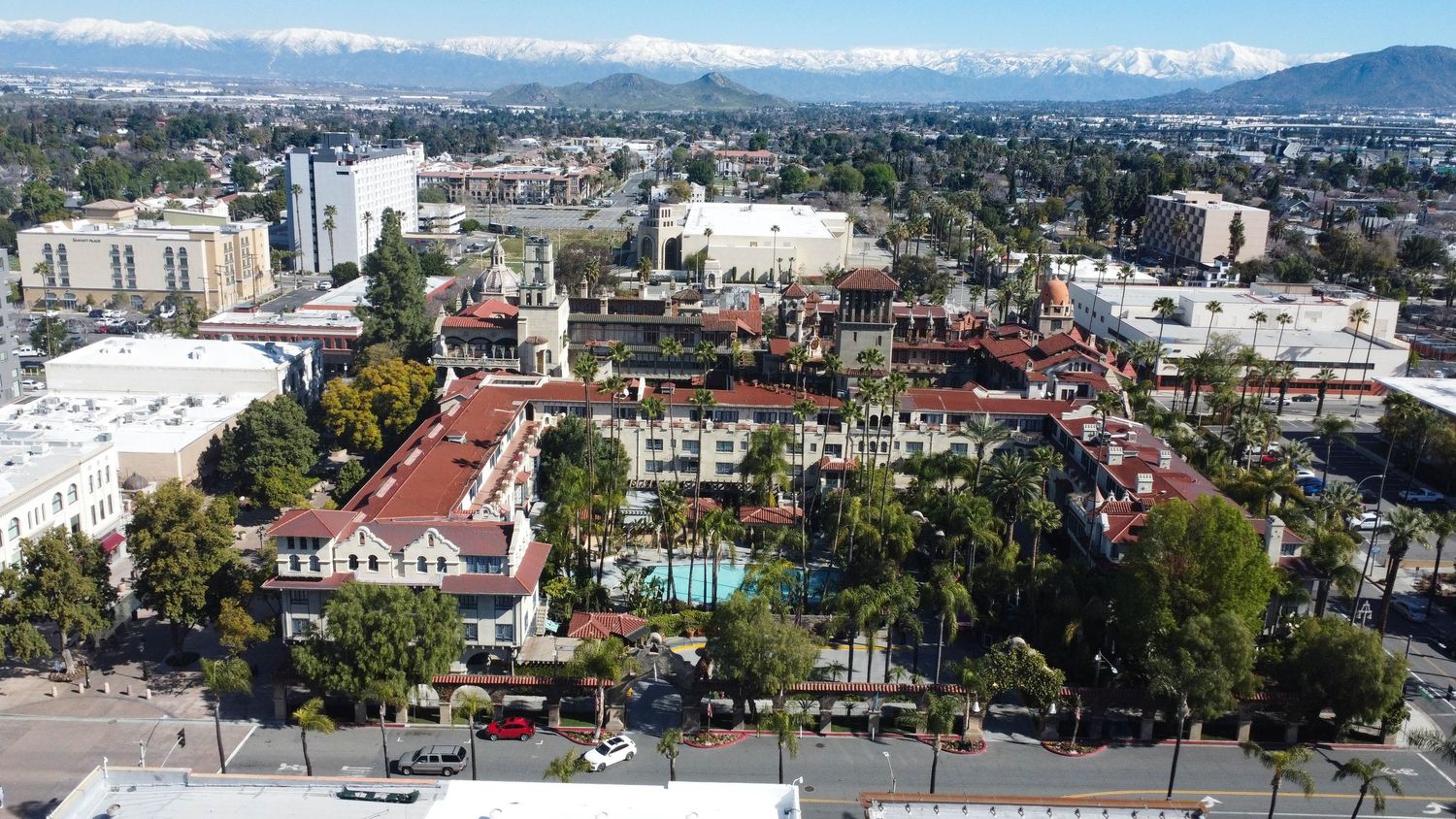 Wide panoramic cityscape view with mountains, residential areas and green spaces.