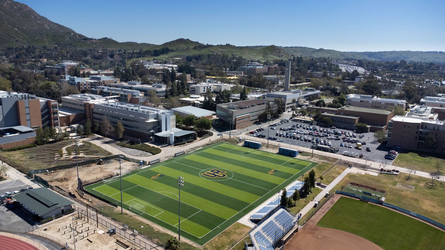 Panoramic aerial view of city with mountains, sports fields and urban development.