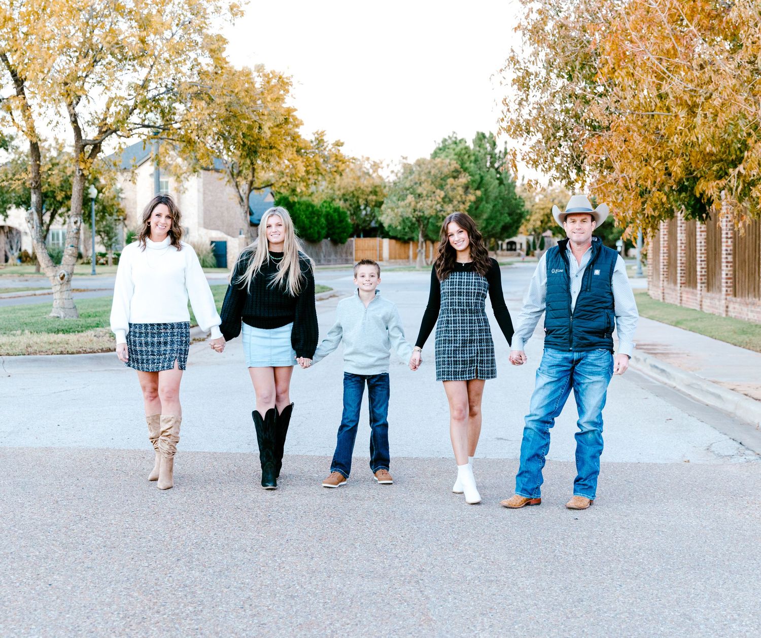 A group of five people walking together on a street during autumn.