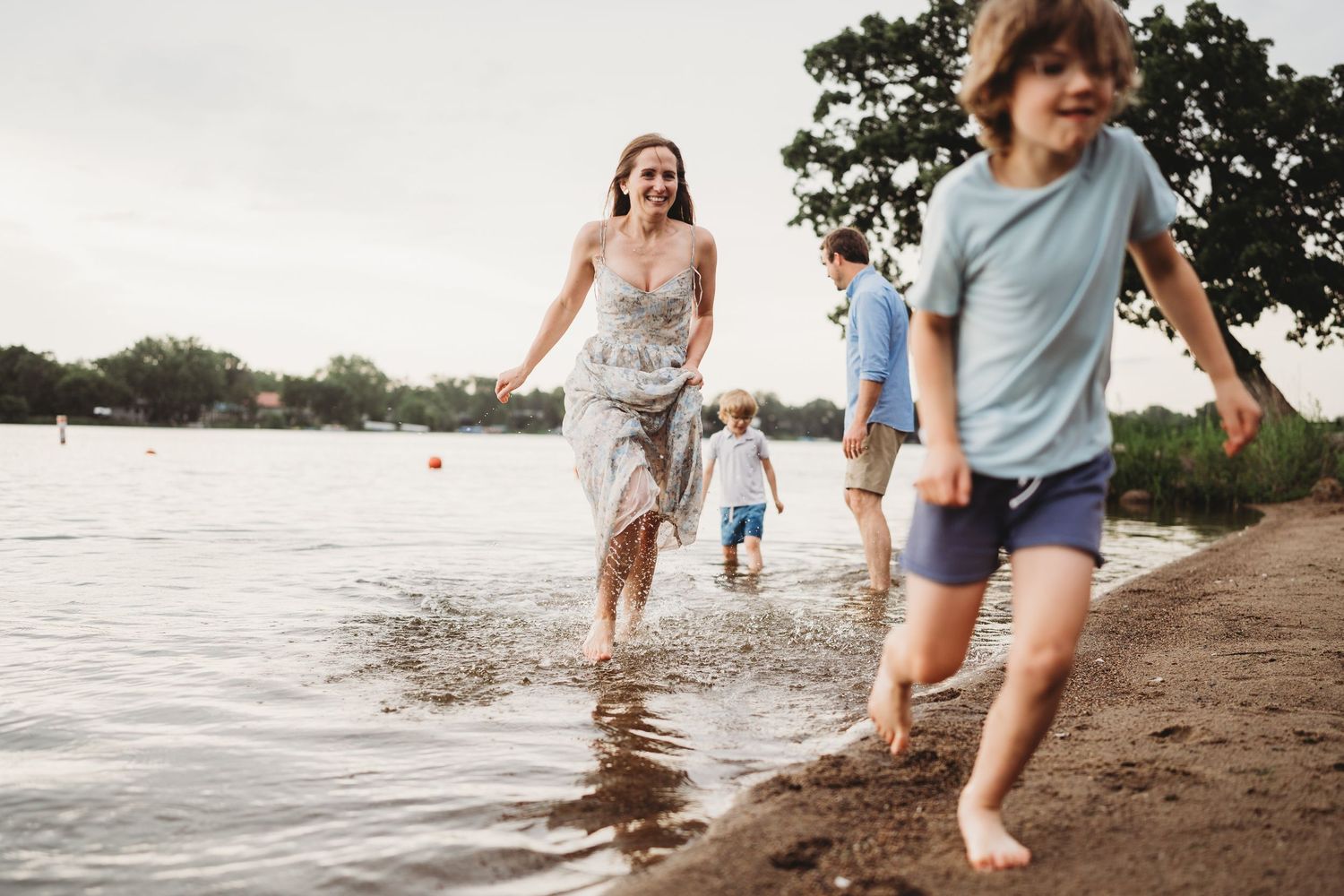 People splashing and playing in the shallow water along a lake shore.