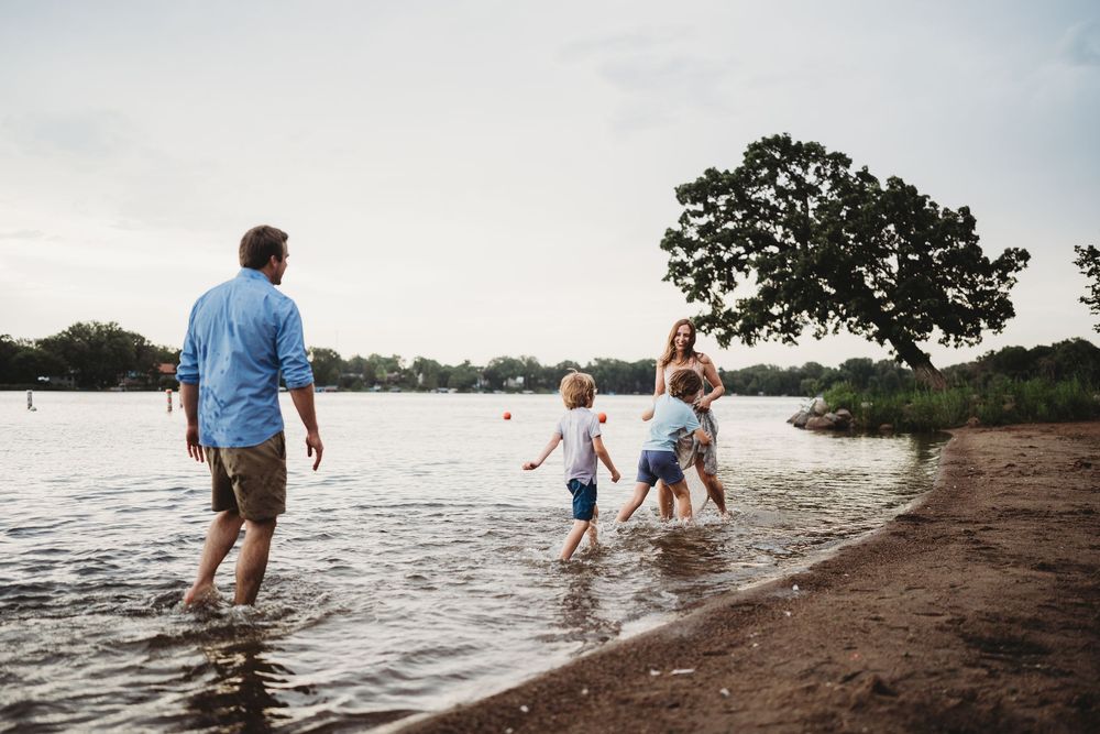 Group wading through shallow lake water during sunset.