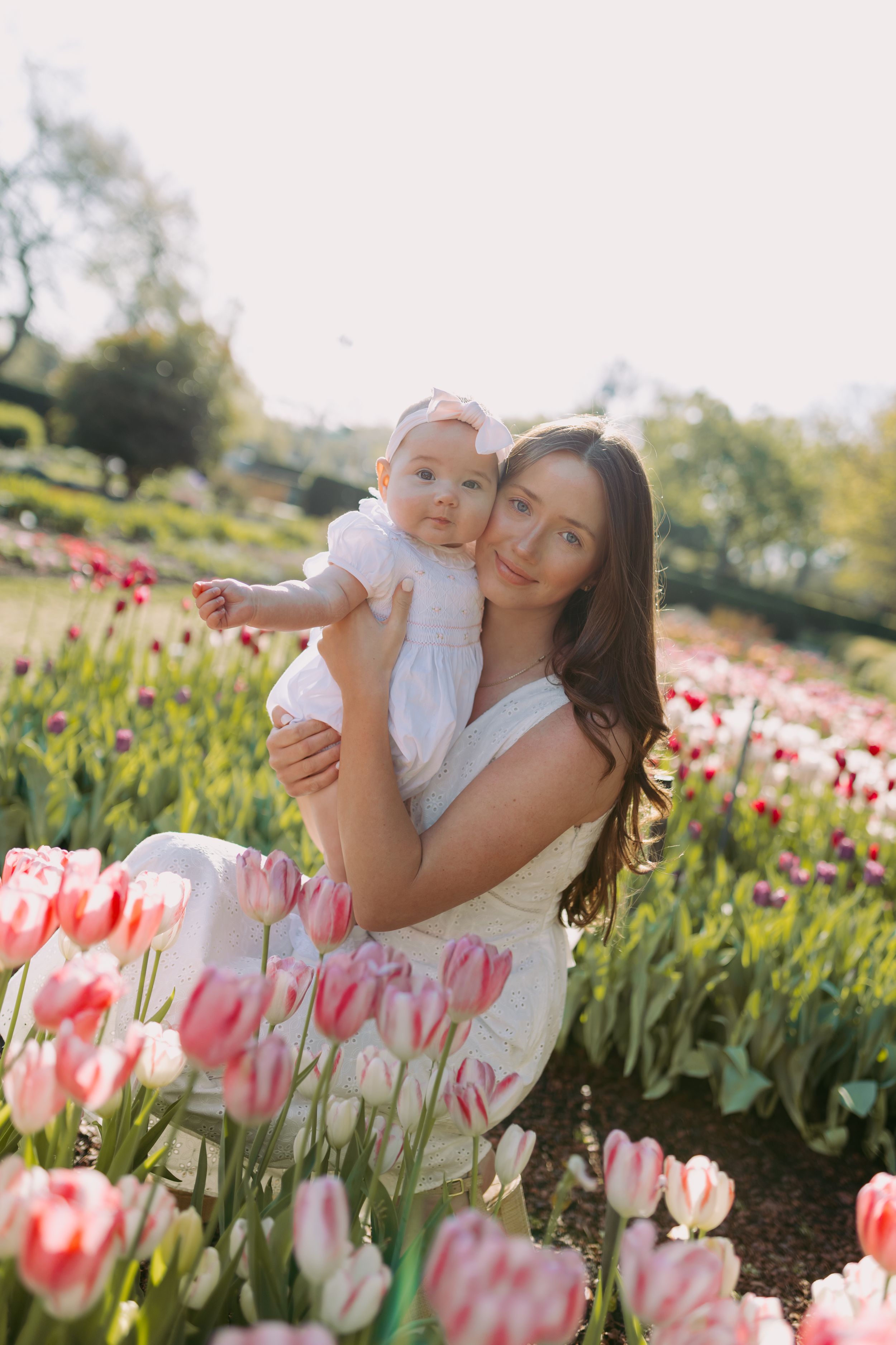 Mother and baby pose together in a vibrant pink tulip garden during springtime.