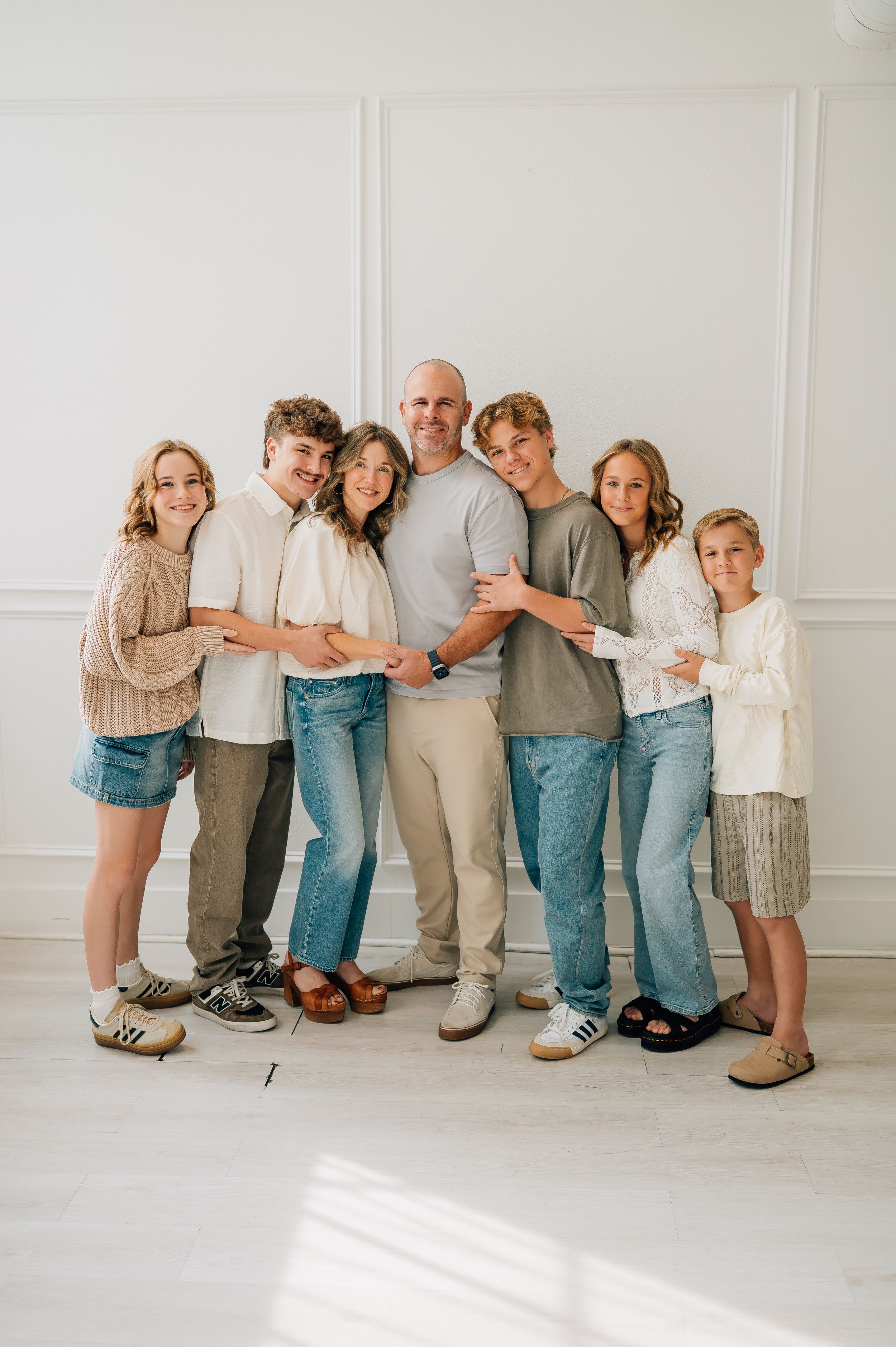 A playful group poses in casual clothing against a white wall in a series of connected photos showing different poses.