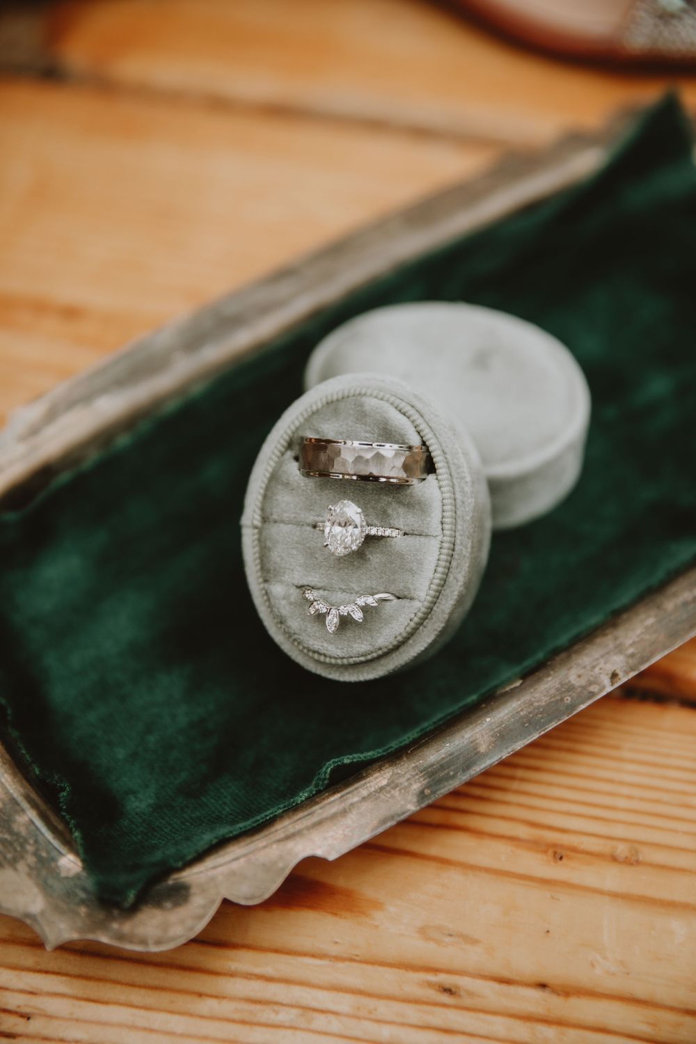 Elegant wedding rings displayed in a velvet ring box on a vintage silver tray with a green velvet lining. Shot by oliviapaigephoto