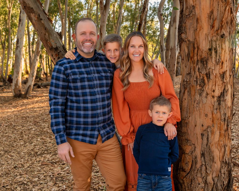 Family fall portraits in a wooded area with eucalyptus trees on an autumn afternoon.