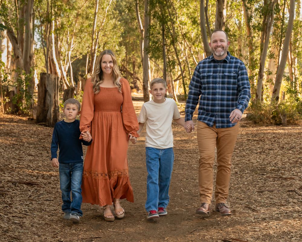 Family fall portraits on a forest trail during golden autumn lighting.