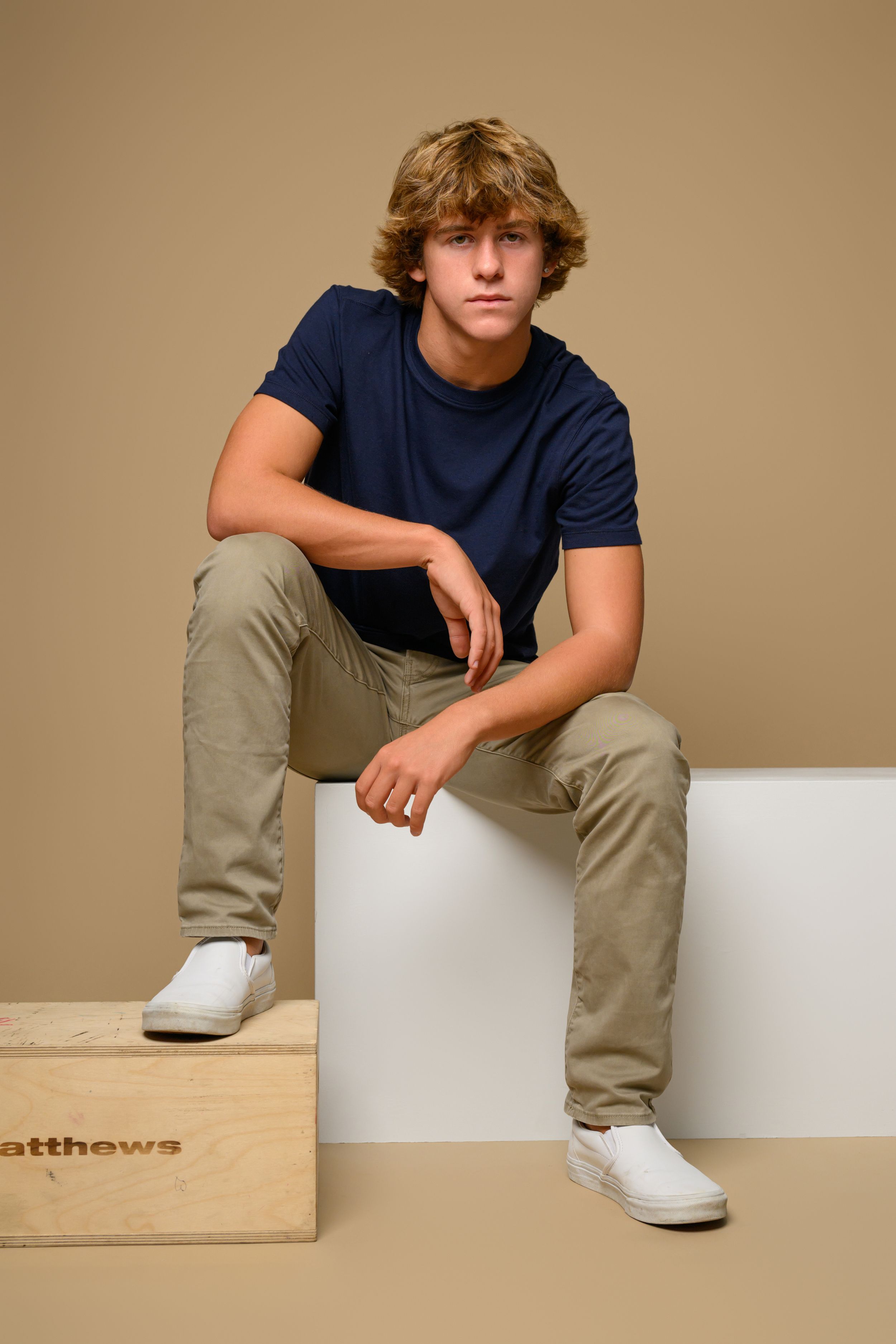Series showing dancer sitting casually on white and wooden blocks wearing navy shirt.