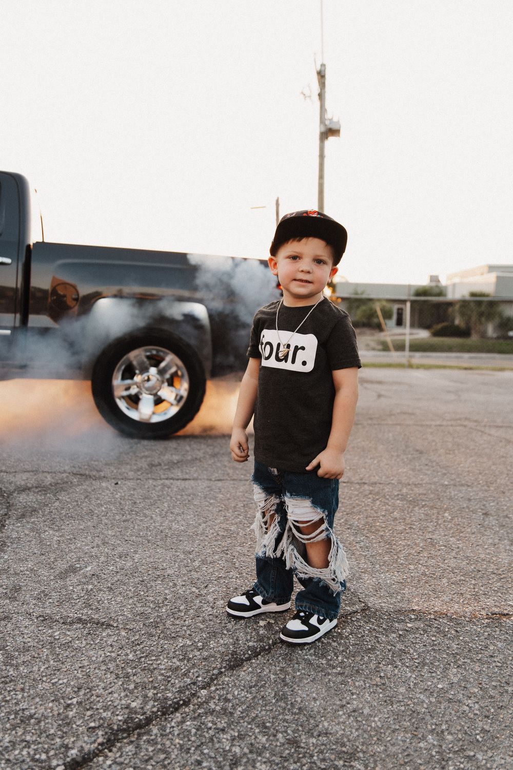 Black t-shirt and shorts on asphalt with smoke in background.