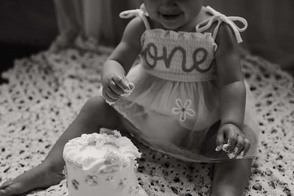 Black and white photo collection showing close-up details of a baby's first birthday party decorations and treats.