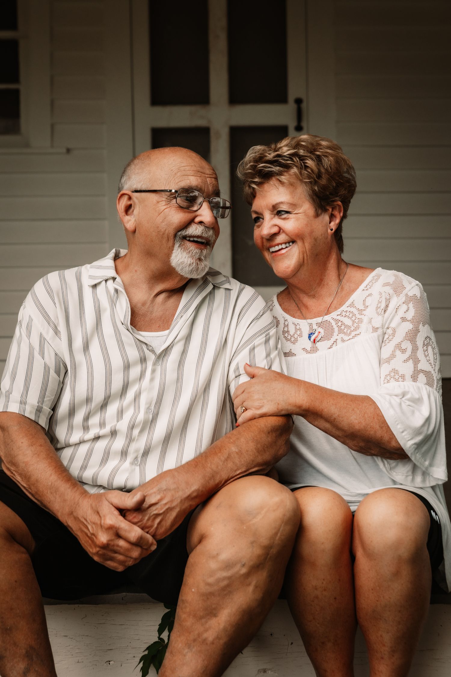 An elderly couple sits together on a porch, laughing and embracing in a series of candid moments.