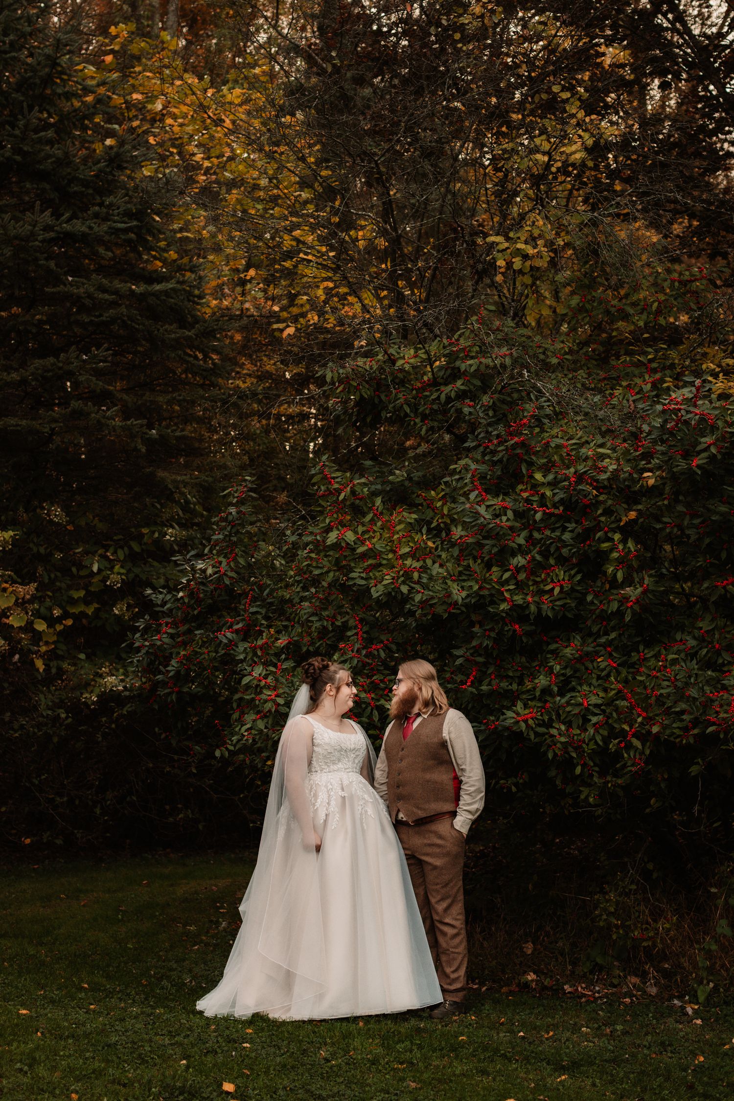 Wedding couple standing in a garden with beautiful fall colors and autumn leaves in the background.