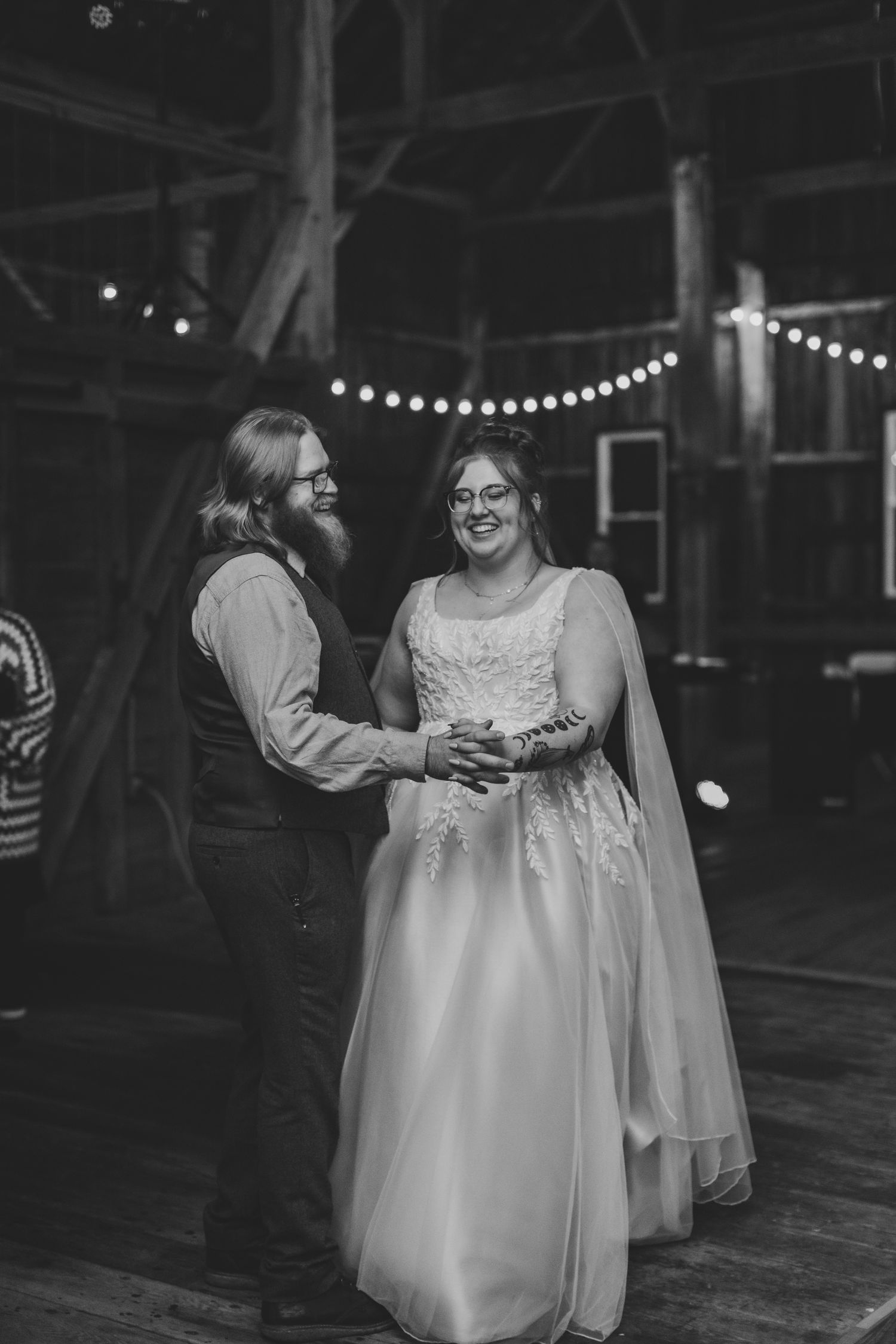 Wedding celebration in a dimly lit barn with string lights creating a romantic atmosphere.