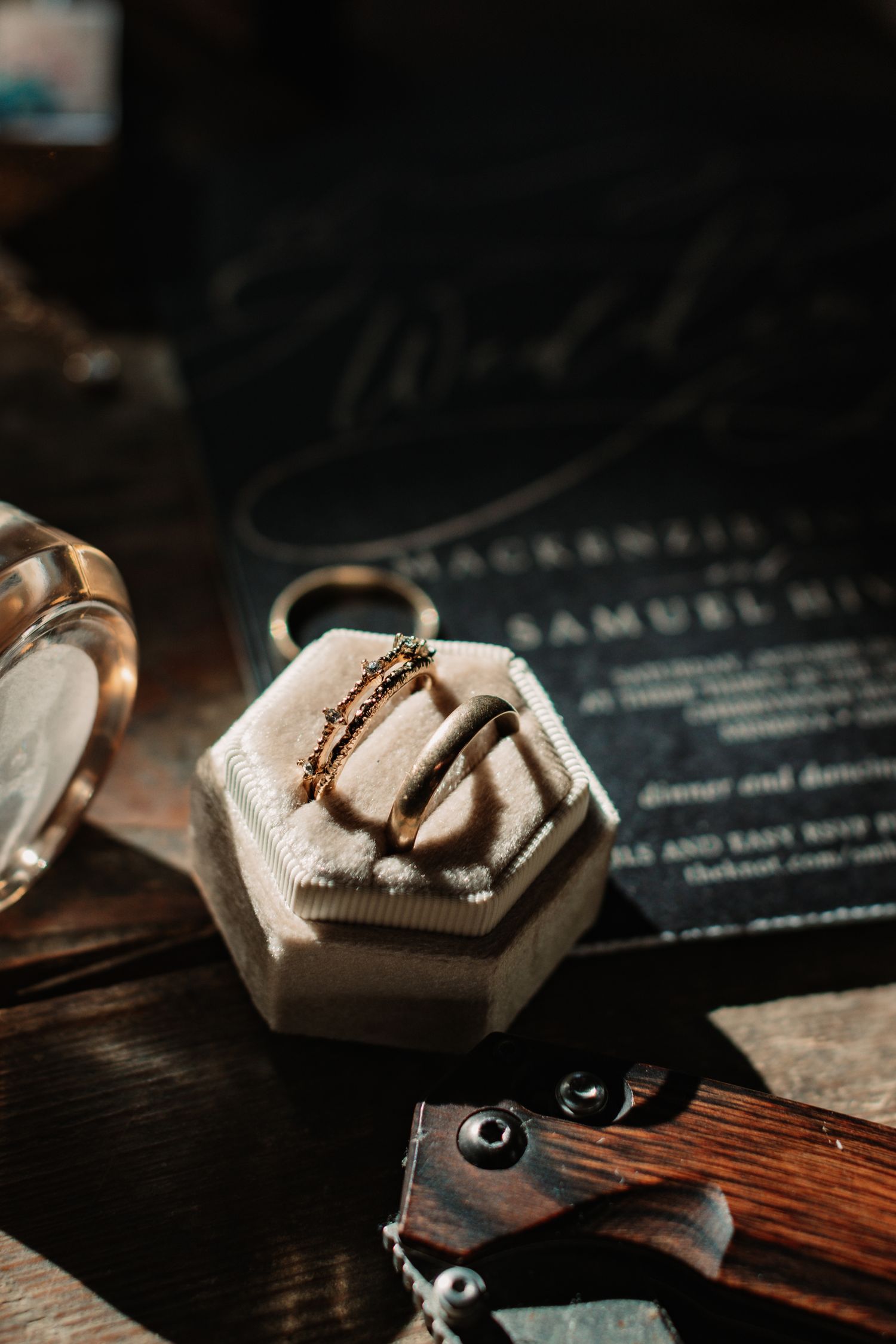 Wedding rings displayed on a rustic wooden surface with elegant black text details in the background.